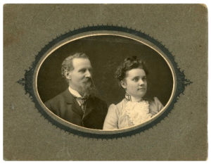 An oval frame displays a vintage photo of a man and a woman